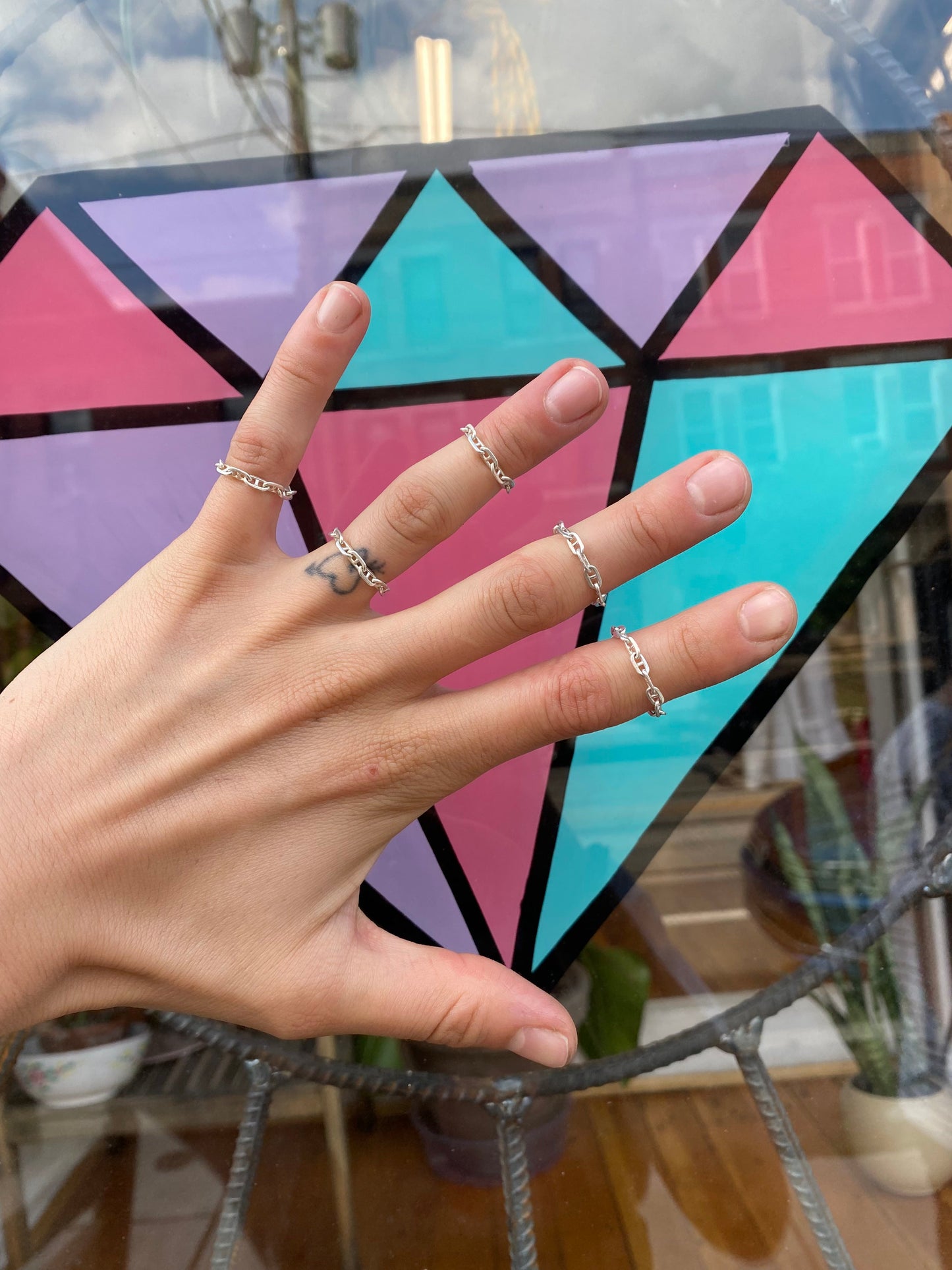 Sterling silver chain rings on a left hand infront of window design.